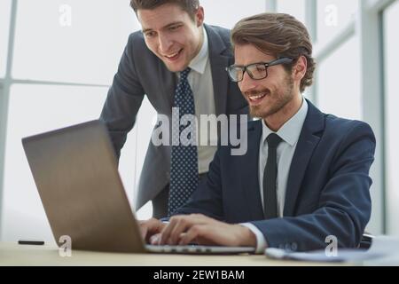 Two businessmen working together on a project sitting at a table in the office Stock Photo