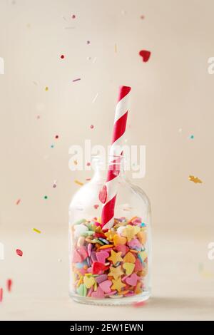 Colorful heart and star sprinkling in a little bottle with striped red and white straw, selective focus Stock Photo