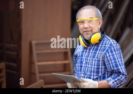 Male carpenter in a construction workshop, using a digital tablet Stock Photo