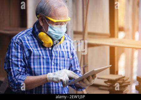 Male carpenter in a construction workshop, using a digital tablet Stock Photo