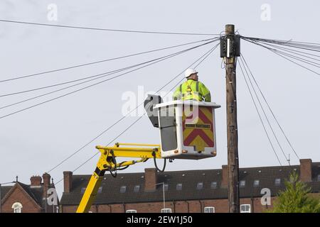 A telecomms power engineer working at height on a lift platform to gain access to a telegraph pole Stock Photo
