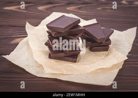 Dark chocolate pieces on a brown background of wooden boards. Sweets, candies on crumpled craft paper Stock Photo