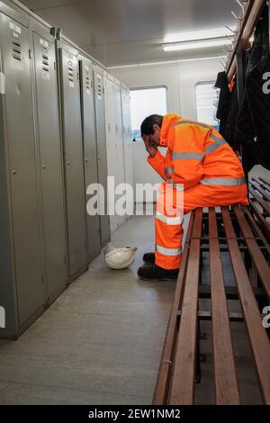 A male employee in the construction or railway industry suffering mental health or grief issues at work Stock Photo