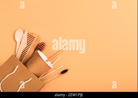Paper and wooden disposable tableware and hygiene items in a paper bag on a beige background. The concept of environmentally friendly tools Stock Photo