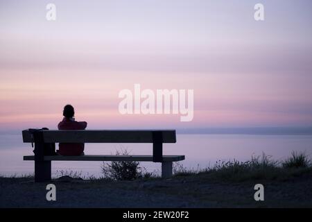 France, Côtes d'Armor, Plerin, young woman at the Pointe du Roselierat sunrise Stock Photo