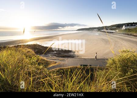 France, Cotes d'Armor, Plérin, young woman walking at dawn along the beach of rosaries Stock Photo