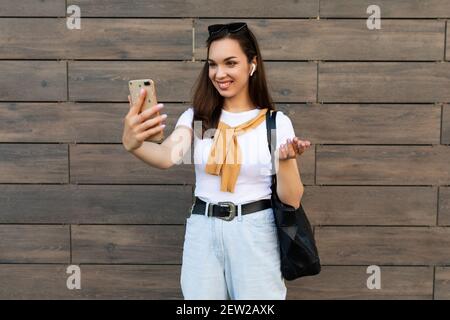 side-profile Photo of beautiful young woman wearing casual clothes standing in the street having communication via mobile phone looking at smartphone Stock Photo