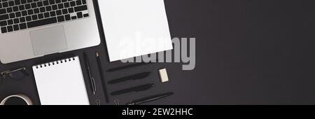 Banner with laptop and office supply on a black background. Online business organized workspace, distance work concept with open notepad mockup. Stock Photo
