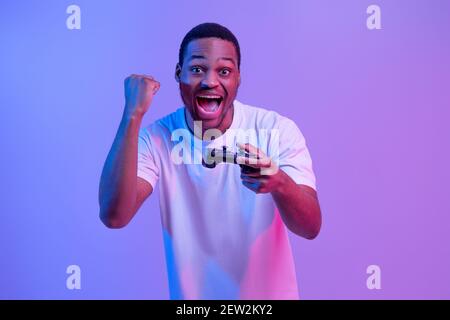 Overjoyed Black Man With Joystick In Hand Celebrating Win In Video Game Stock Photo