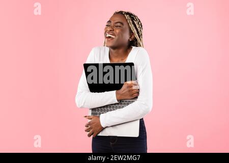 Excited black woman hugging personal computer at studio Stock Photo - Alamy