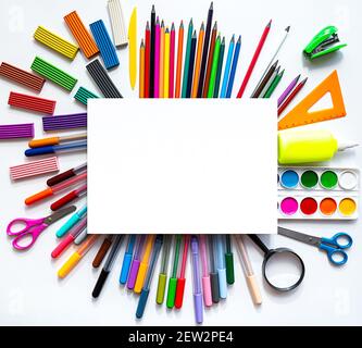 Bright still life scene of stationery on a white background. Colored pencils, felt-tip pens, plasticine and paints, flat lay with a place for text. Stock Photo