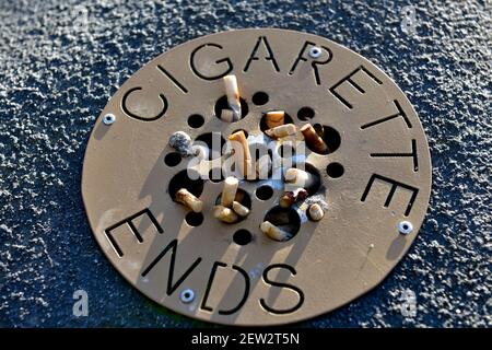 Cigarette ends in public ashtray Stock Photo