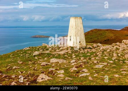 The trig point above the sandy beach at Rhossili Bay on the south west coast of the Gower Peninsula near Swansea in South Wales UK Stock Photo