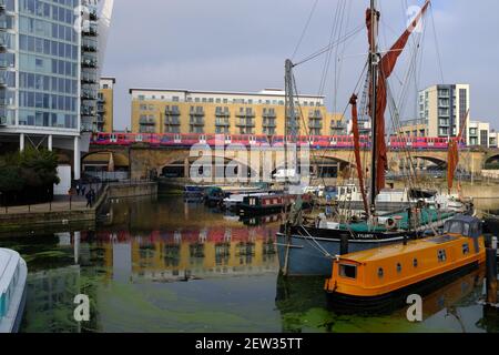 LONDON - 2ND MARCH 2021: The Limehouse Basin in Limehouse. A Dockland Light Railway train passes by in the background.