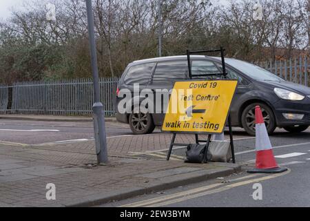a car stops at give way junction where a road sign of covid 19 test centre is place on road side Stock Photo