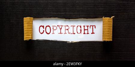 Copyright symbol. The word 'Copyright' appearing behind torn black paper. Beautiful black background. Business, copyright concept. Copy space. Stock Photo