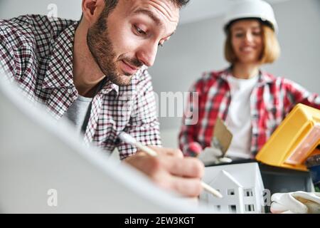 Joyous woman painter looking at a working dark-haired bearded draftsman Stock Photo