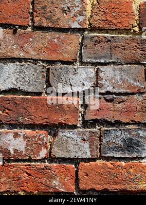 Part of a wall made of old bricks of varying shapes and colours. Stock Photo
