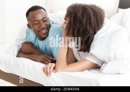 Young relaxed beautiful couple lying in bed at morning at weekend Stock Photo