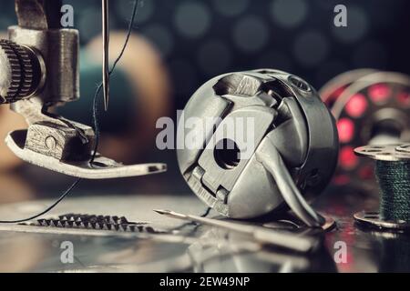 Close up on foot of vintage sewing machine, metal shuttle and spool of thread. Stock Photo