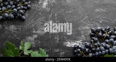 Black juicy grapes on vintage dark concrete background. Frame made of grapes . Copy space for text or menu on black scuffed background. Fruit berry Fr Stock Photo
