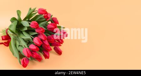 A large bouquet of red tulips lies on a yellow background - spring flowers for the holiday of March 8 or Valentines Day. Banner. Copy space Stock Photo