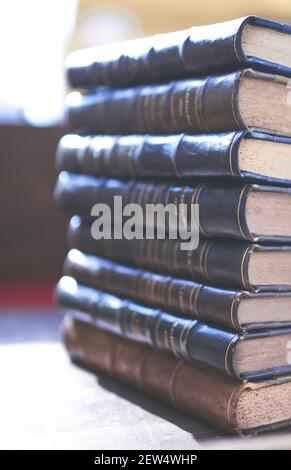 several old and slightly worn books stacked in a tower on a desk Stock Photo