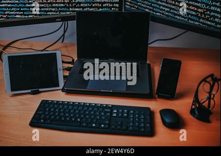 A closeup of programmer's desk with types of electronic equipment displaying codes Stock Photo