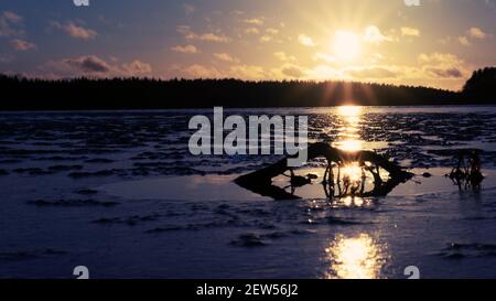 The dull sun of a winter sunset over a frozen lake and forest Stock ...
