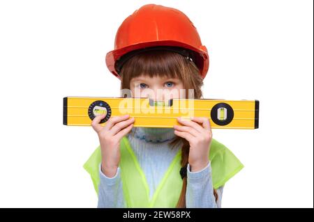 Preschool child girl wearing construction vest and building helmet holds level on white isolated background Stock Photo