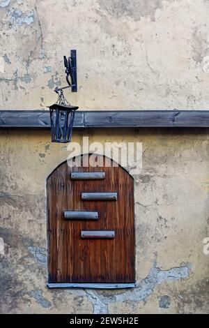 Arched window on an old plastered wall closed by wooden shutters with a street lamp. From the window of the world series. Stock Photo