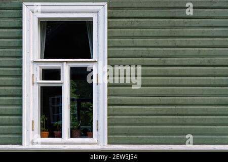 Rectangular window with a white frame on the background of a wall made of dark green wooden planks. From the window of the world series. Stock Photo
