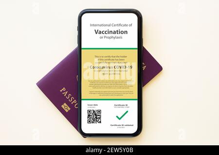 Flat lay with copy space, a passport and a smartphone with a Certificate of Vaccination against Covid-19 disease are arranged on a table. Stock Photo