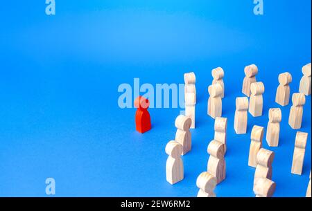 A figurine of a red man stands aside from the crowd of people. Stand out. Leadership qualities concept. Lead people with you. Be in the spotlight. Rej Stock Photo