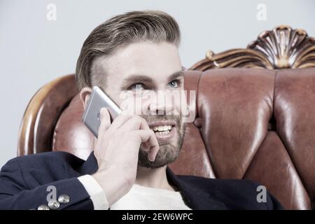 Man or businessman smile and talk on smartphone on sofa. Business communication concept. Entrepreneurship, new technology, modern life. Stock Photo