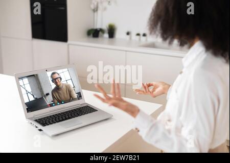 African American female entrepreneur businesswoman using application for distance video communication looking at laptop, discussing project with male colleague or client, staying connected in pandemic Stock Photo