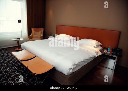 Moscow, Russia - February 13, 2021: Typical hotel room. Bed is covered  Stock Photo