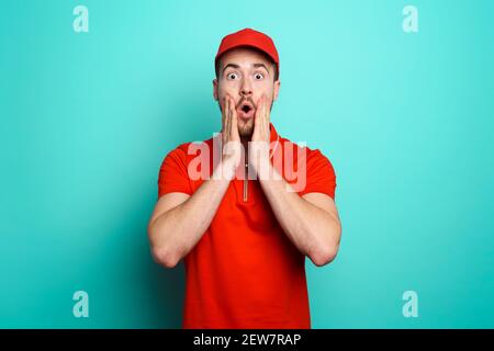 Courier with a wondered expression about a great promotion. cyan background Stock Photo