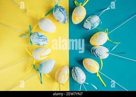 Easter composition. Decorative eggs are laid out on a two-tone yellow-blue background. copy space. Stock Photo
