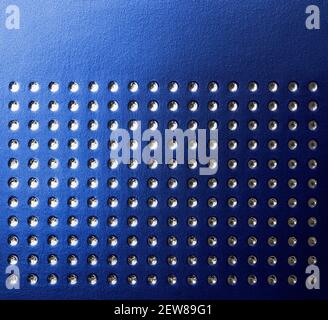 Macro of blue textured paper with concave silver dots pattern. Symmetrical rows of depressed shiny dots on indigo surface Gradient geometry background Stock Photo