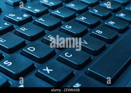 Closeup of the black computer keyboard on blue tone. Distance learning, online work, business and shopping, confirm product order or agreement concept Stock Photo