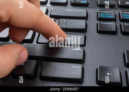 Person finger peessed down the enter key on the black computer keyboard. Distance learning, online work, business and shopping, confirm product order Stock Photo