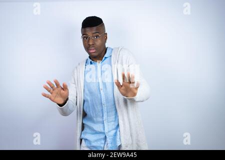 Young handsome african american man wearing casual clothes afraid and terrified with fear expression stop gesture with hands, shouting in shock. Panic Stock Photo