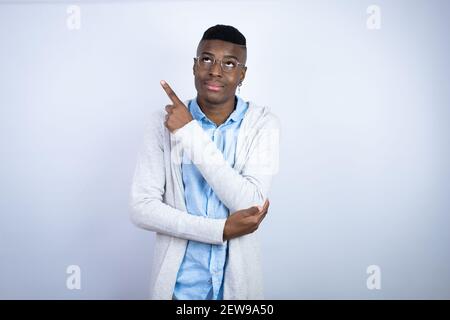 Young handsome african american man wearing casual clothes confused and pointing with hand and finger to the side Stock Photo