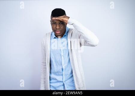 Young handsome african american man wearing casual clothes very happy and smiling looking far away with hand over head. searching concept. Stock Photo