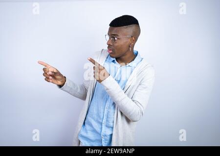Young handsome african american man wearing casual clothes surprised and pointing his fingers side Stock Photo