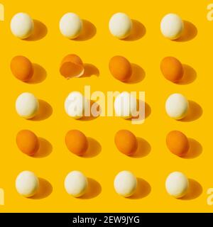 Chicken fresh and boiled eggs pattern with one empty broken eggshell on yellow background. Healthy food or Easter creative minimal concept. Flat lay Stock Photo