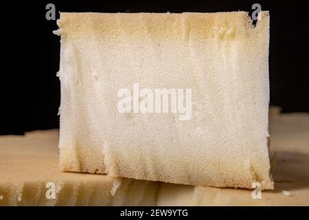A cut sponge in an upholstery workshop. The material used to build soft sofas and armchairs. Dark background. Stock Photo