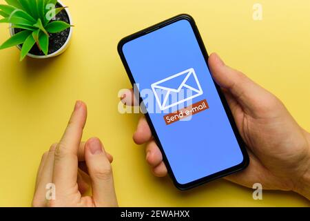 Person sends an email using a smartphone in his hands. Stock Photo
