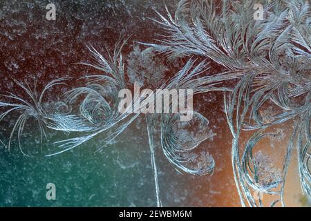 Jack Frost etchings on the window, with a colourful background. Stock Photo